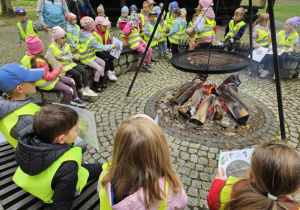 Dzieci siedzą wokół ogniska.