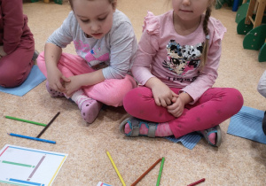 Dwie dziewczynki odzwierciedlają wzór z karki za pomocą kolorowych kredek.