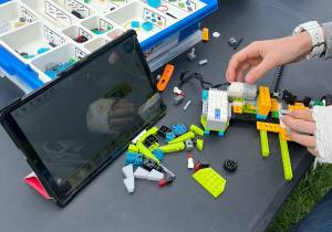 zdjęcie przedstawia klocki lego, tablet i instrukcję jak stworzyć robota z klocków lego